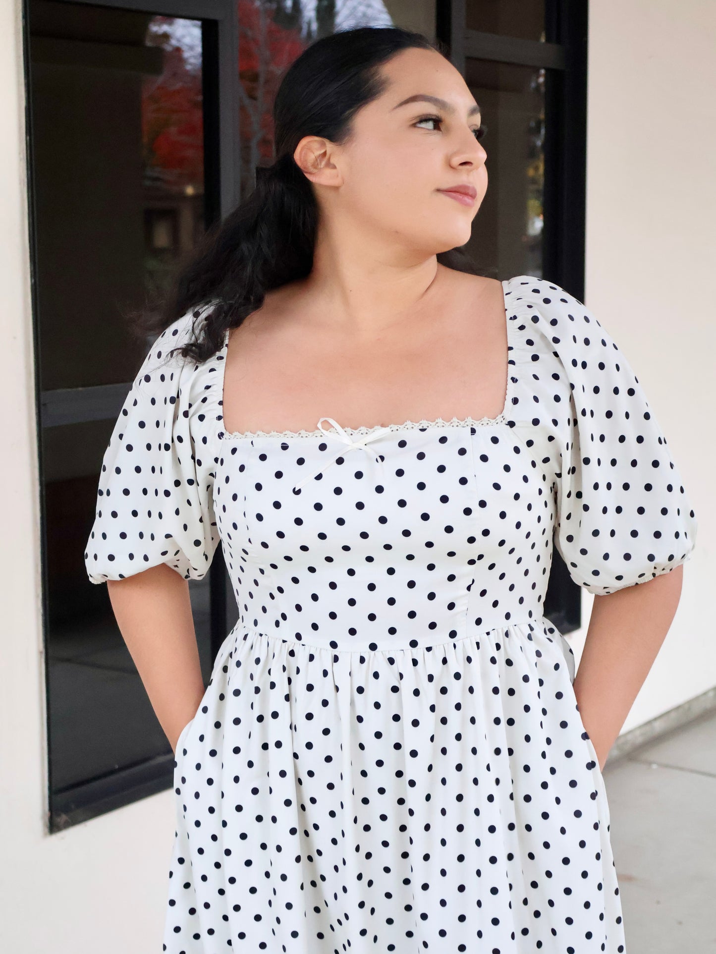Woman wearing a polka dot dress standing outdoors.